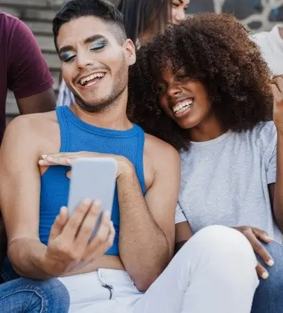 Diverse people smiling and looking at a phone.
