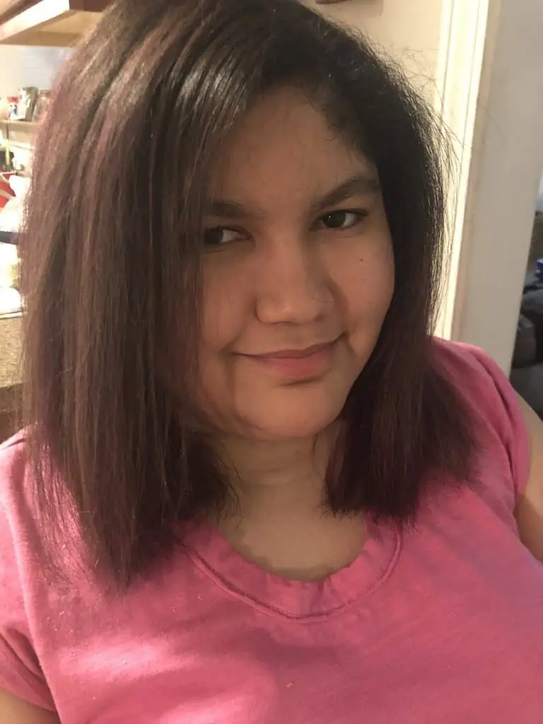 Una mujer latina con una camisa rosa y cabello castaño alto