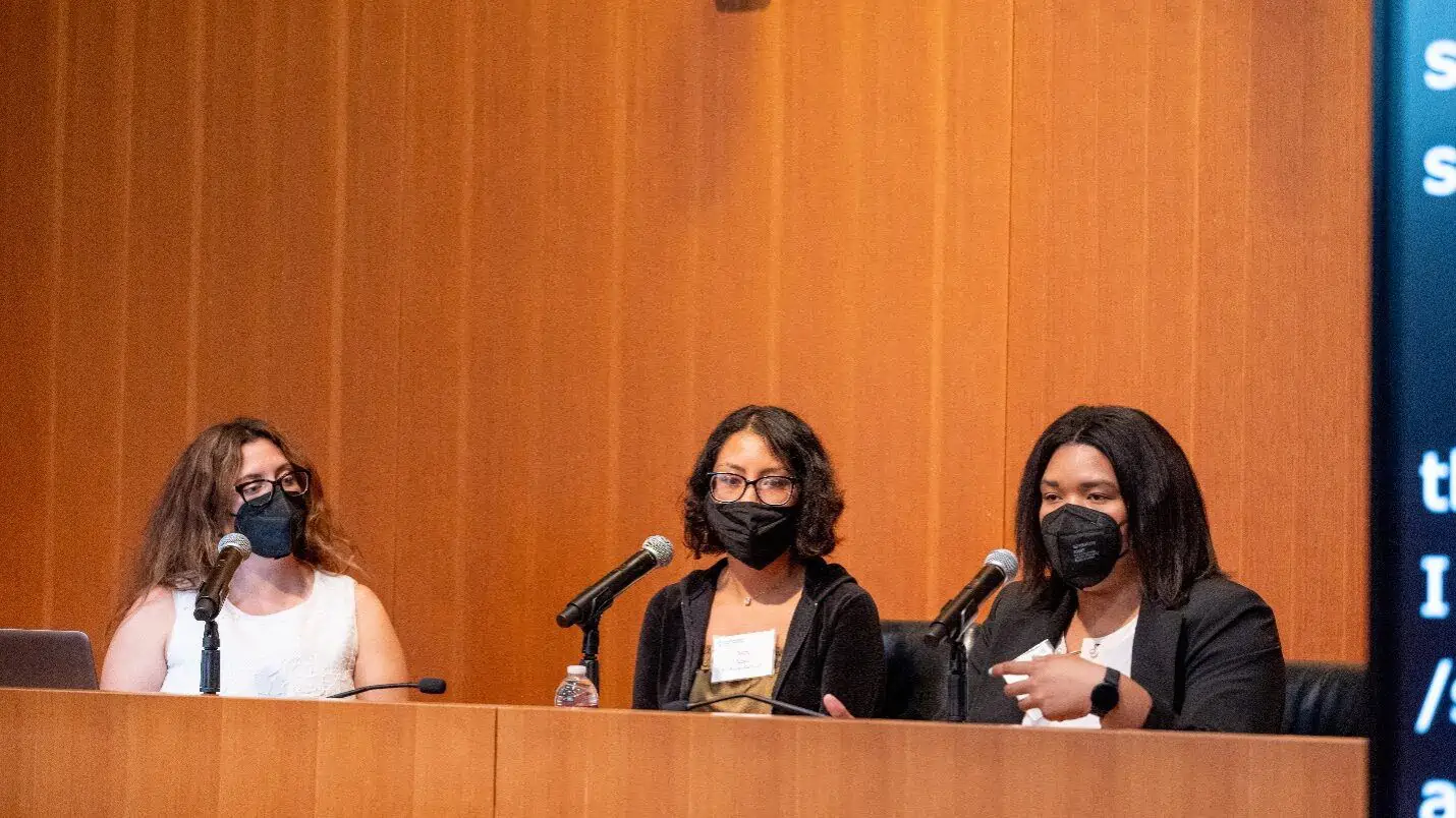 A panel seated with microphones at the Coelho Law Center.  From left to right: Katherine Perez, Nira Nova and Angelica Vega