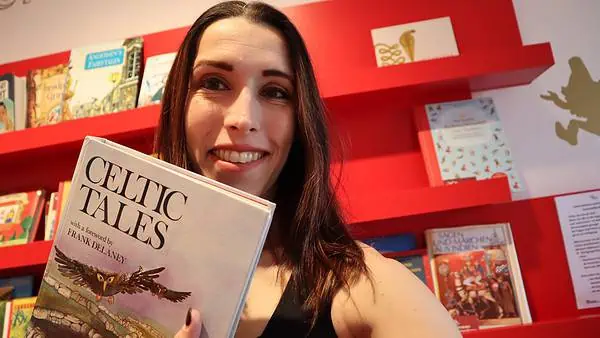 Kayley Whalen holding the book Celtic Tales with a foreward by Frank Delaney