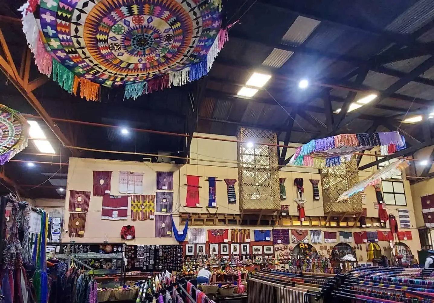 Guatemalan textile shop in Antigua with large fringed Octagonal kites in bright colors hanging from the ceiling.