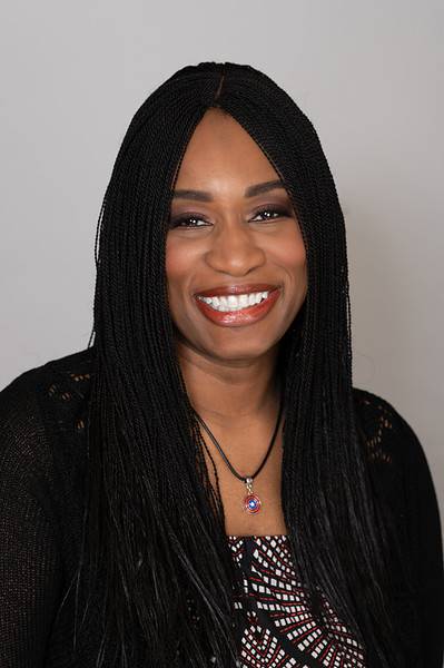 Morénike Giwa Onaiwu smiling Black autistic woman with long black hair wearing a black cardigan